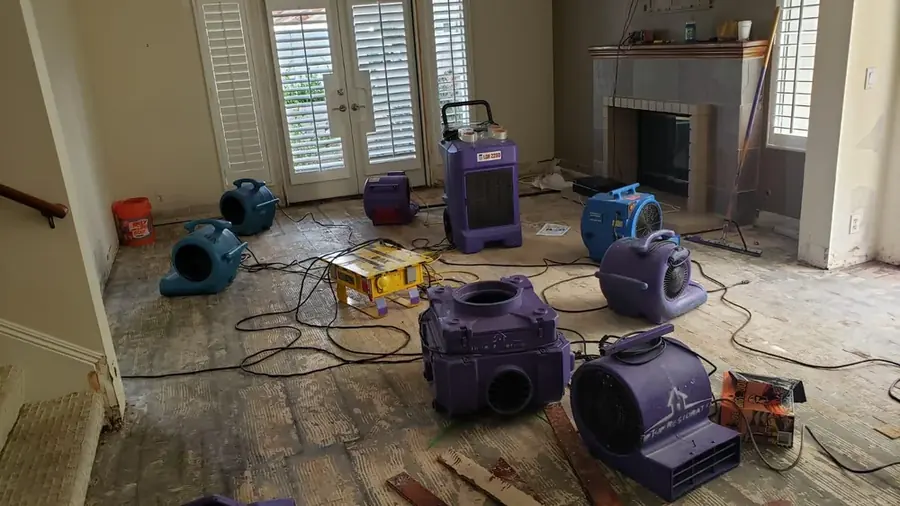 Air movers and a dehumidifier drying a Natick room after a leak